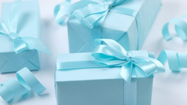 Rotating blue gift boxes with blue bows on a blue background,, the concept of celebrating a boy or man's birthday, a party or an anniversary or a newborn