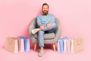 Full length portrait of cheerful man sit chair rest relax shopping packages isolated on pink color...