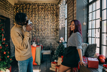 Cheerful young man and woman taking photo at home decorated for Christmas winter holiday. Happy family training together
