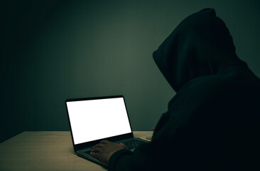A hacker in black is using a laptop on a desk to hack the system.Cyber attack, system breaking and malware concept.