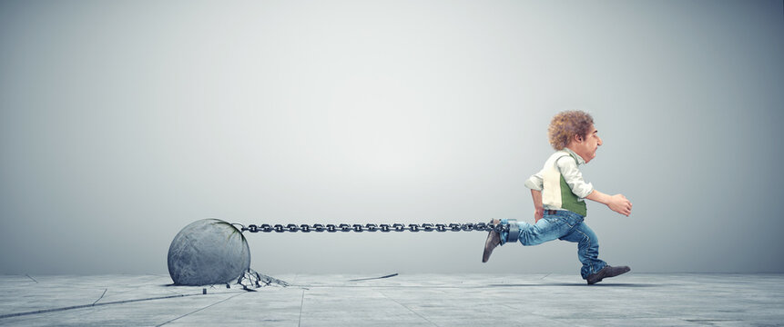 Man dragging a ball and chain. The burden of financial debt.
