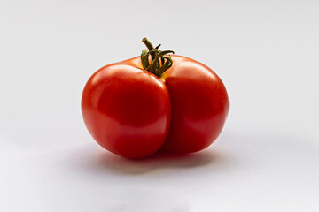 Wonky shaped and imperfect tomato in a suggestive shape, shot in a white studio.