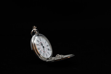 An old pocket watch on black background, copy space
