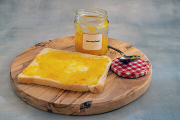 Homemade marmalade jam with a spoon on a wooden plate, copy space