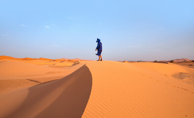 Fototapeta na wymiar Happy bedouin in traditional bright clothing standing on sand in sahara desert - Sahara, Morocco