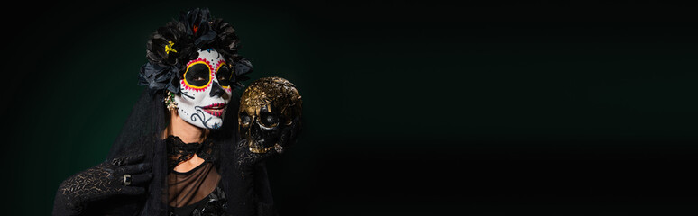 Woman in santa muerte costume holding skull on dark green background, banner.