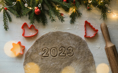 Top view of gingerbread dough and cookies in the form of numbers 2023. New Year's gingerbread 2023