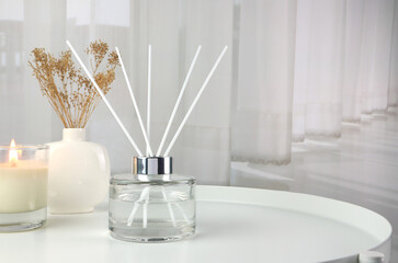 luxury aroma scent reed diffuser glass bottle is on white steel table with clear glass of scented...
