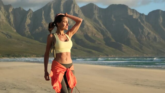 athletic muscle woman running on beach. Beautiful teenage sport woman doing stretching exercise on sand beach. sports girl in a tank top and leggings walks along the ocean beach with a skipping rope