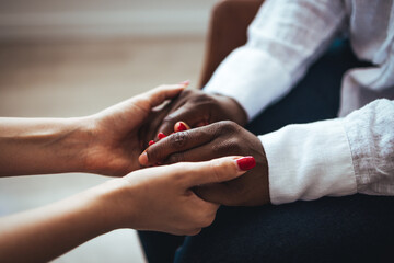 Biracial female psychologist hands holding palms of millennial woman patient. Cropped image of woman comforting her friend. Shot of two unrecognizable women holding hands together ....