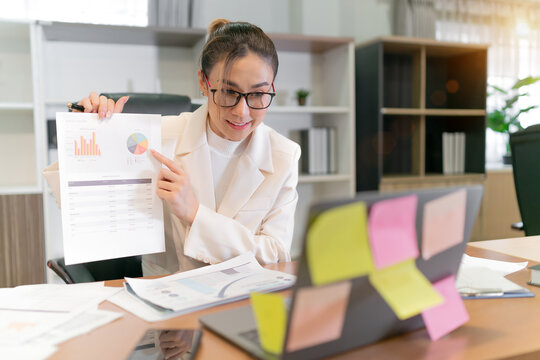 beautiful asian business woman present work. professional female worker showing paper sheet information to online meeting team. office employee holidng plan paper for internet video business group