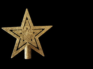 Gold star to be placed on top of the Christmas tree, isolated on a black background.