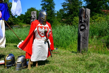 A close up on a set of medieval knight armor with a Polish crest on the chestpiece seen next to...