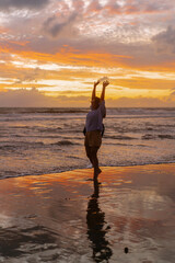 Fototapeta na wymiar Happy woman dancing at sunset on the ocean, yellow light.