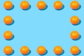 Creative frame of tangerines on a blue background