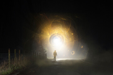 A sci fi concept of a figure standing in front of a glowing portal. On a spooky country road on a...
