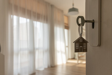 Open door to a new home with key and home shaped keychain. Mortgage, investment, real estate, property and new home concept - obrazy, fototapety, plakaty