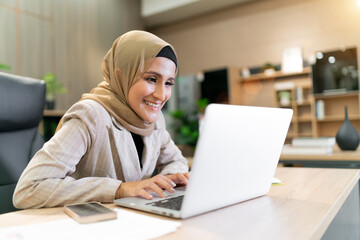 happy business muslim hijab woman work. the cheerful female islam worker looking at laptop talking...