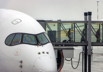 A passengers get out of the plane into the tunnel at a winter airport with falling snow