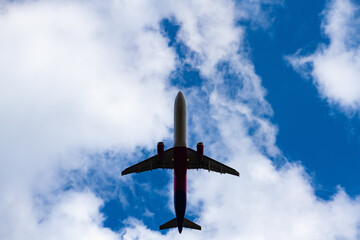 Jet plane taking off with blue sky and white clouds. Symmetric silhouette of modern passenger air...