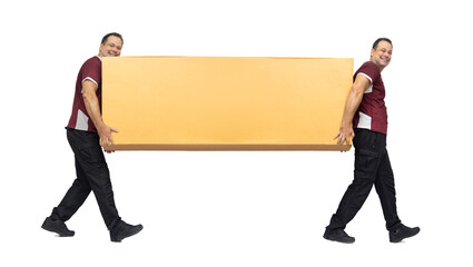 Two smiling men carry a large package, isolated on white background.