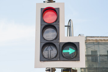 Close-up of a traffic light with a red light and a green arrow pointing to the right side.