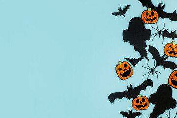 Halloween. Black ghosts, spiders, bats and orange pumpkins decorations on blue background flat lay. Happy Halloween! Card template with space for text. Modern minimal border