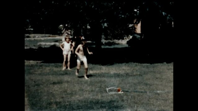 Running Through the Sprinkler 1967 - Siblings take turns running through a lawn sprinkler at their home in Canoga Park, California in 1967.
