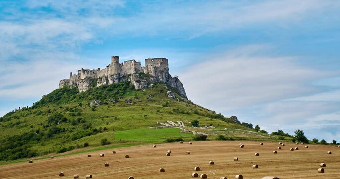 Timelaps Castle, Spissky Hrad In Slovakia with clouds and straw bales background