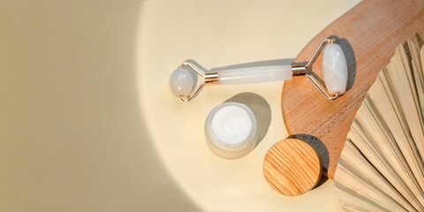 Top view of facial roller for massage on wooden slice.Pastel colors,eco friendly concept.