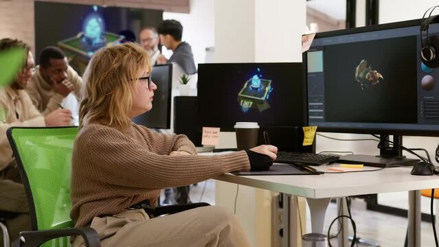 Caucasian female artist designer in glasses drink coffee and draws on a tablet a 3D model for a computer game in the office of a project development studio. 