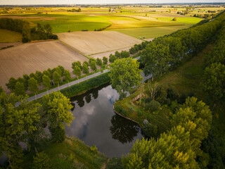 Aerial view of pond and tree lined canal of Schipdonk with agriculture and meadows in the background