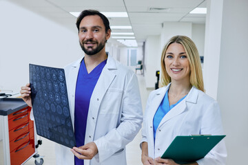 Radiographer with MRI of patient head is standing in corridor of hospital with female radiologic...