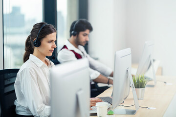 A team of customer support representatives talk to each other at the office. Consulting technical support. Attractive call center agents. Customer service team support concept. Sales department.