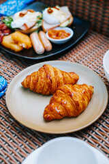 Two croissants are placed on the brown plate with blurred background