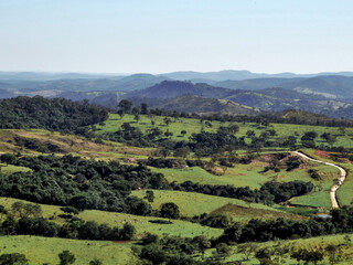 Naklejka premium Linda vista de fazenda, com lago artificial, muita vegetação, montanhas ao redor e uma estrada no meio. localizada na região rural do bairro Jardim das Oliveiras, município de Esmeraldas, Minas Gerais