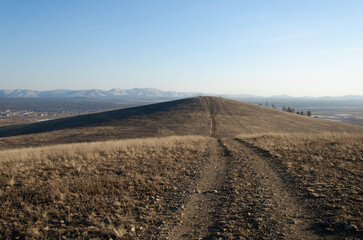 Dirt road through the hills. Autumn, mountainous terrain in the steppe, through which the road runs.