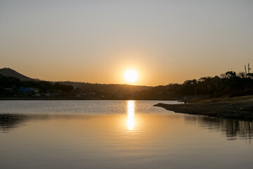 Lindo pôr do sol ao entardecer com céu limpo, com reflexo em lago no bairro Jardim das Oliveiras, Esmeraldas, Minas Gerais, Brasil.