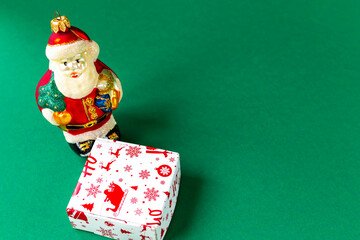 Toy Santa Claus and gift box on a green background. Top view