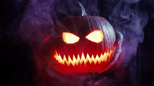 Burning fearful symbol of Halloween - Jack-o-lantern under neon color light. Scary smoky smiling head of pumpkins close-up. Glowing face, trick or treat.