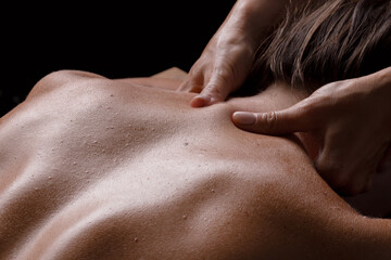 masseur girl makes a massage close-up on a dark background. close-up massage