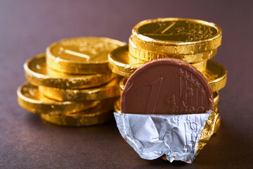 Chocolate coin. Backgrounds of chocolate Euro coin money on brown background. Euro coins stacked on...