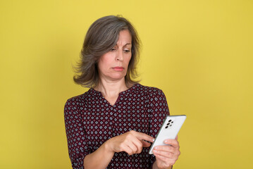 Fototapeta premium Pensive mature woman reading text message on cell phone 