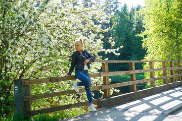 A beautiful girl poses near a blossoming tree in spring in Estonia.