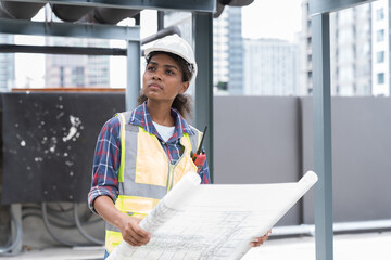 Female engineer working with construction building blueprint at sewer pipes area at construction site on rooftop of building - obrazy, fototapety, plakaty
