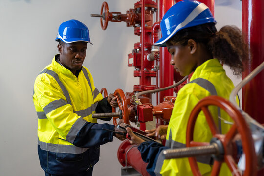 Team of engineer or technician maintenance, checking, or test system springer prevent fire. Group of African American contractor checking fire sprinkler system, pipe assembly, red fire pipe