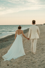 Fototapeta na wymiar Newlywed couple walking on the beach of Tarragona in Spain.