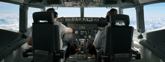 Commercial aircraft pilots adjusting flight parameters of the plane during the flight at high...