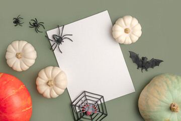 Blank paper sheet with Halloween decorations on pastel green background. Greeting card, invitation mockup. Place for inscription. Pumpkin. Modern Minimal invite mock up, template. Flat lay, top view