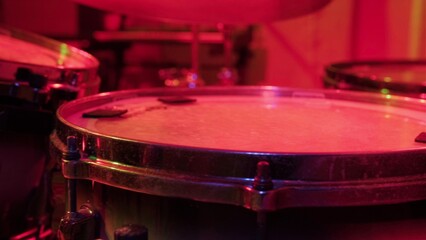 Fototapeta na wymiar Drummer rehearsing on drums before rock concert. Man recording music on drum set in studio in red light